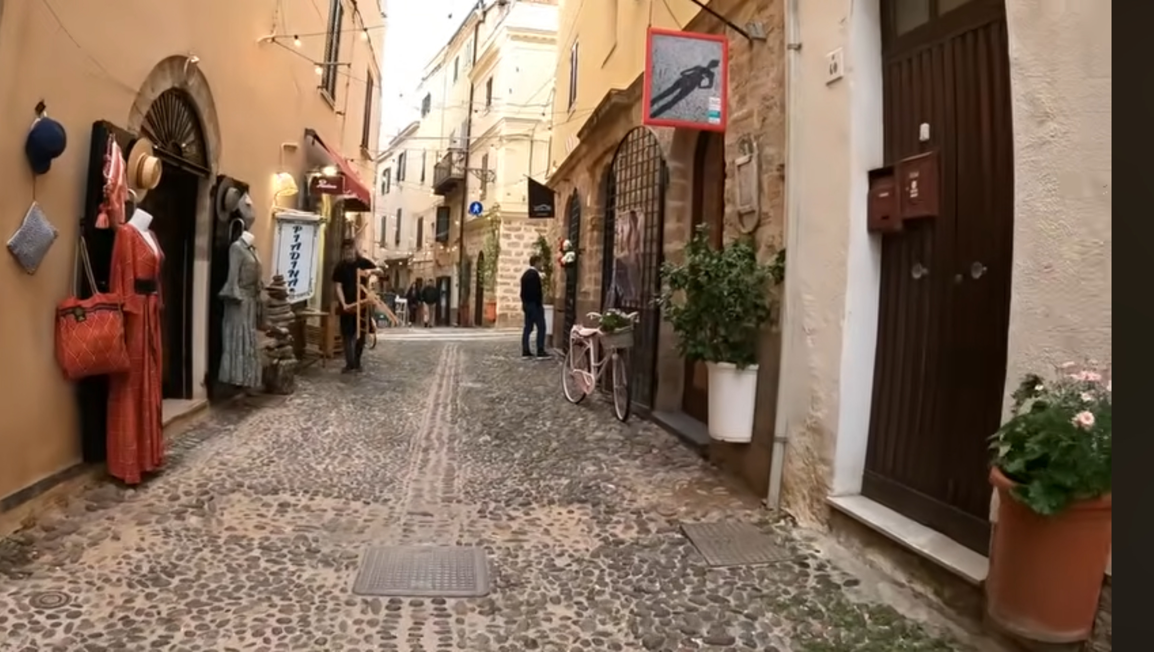 Cobblestone street lined with shops in Alghero's historic center