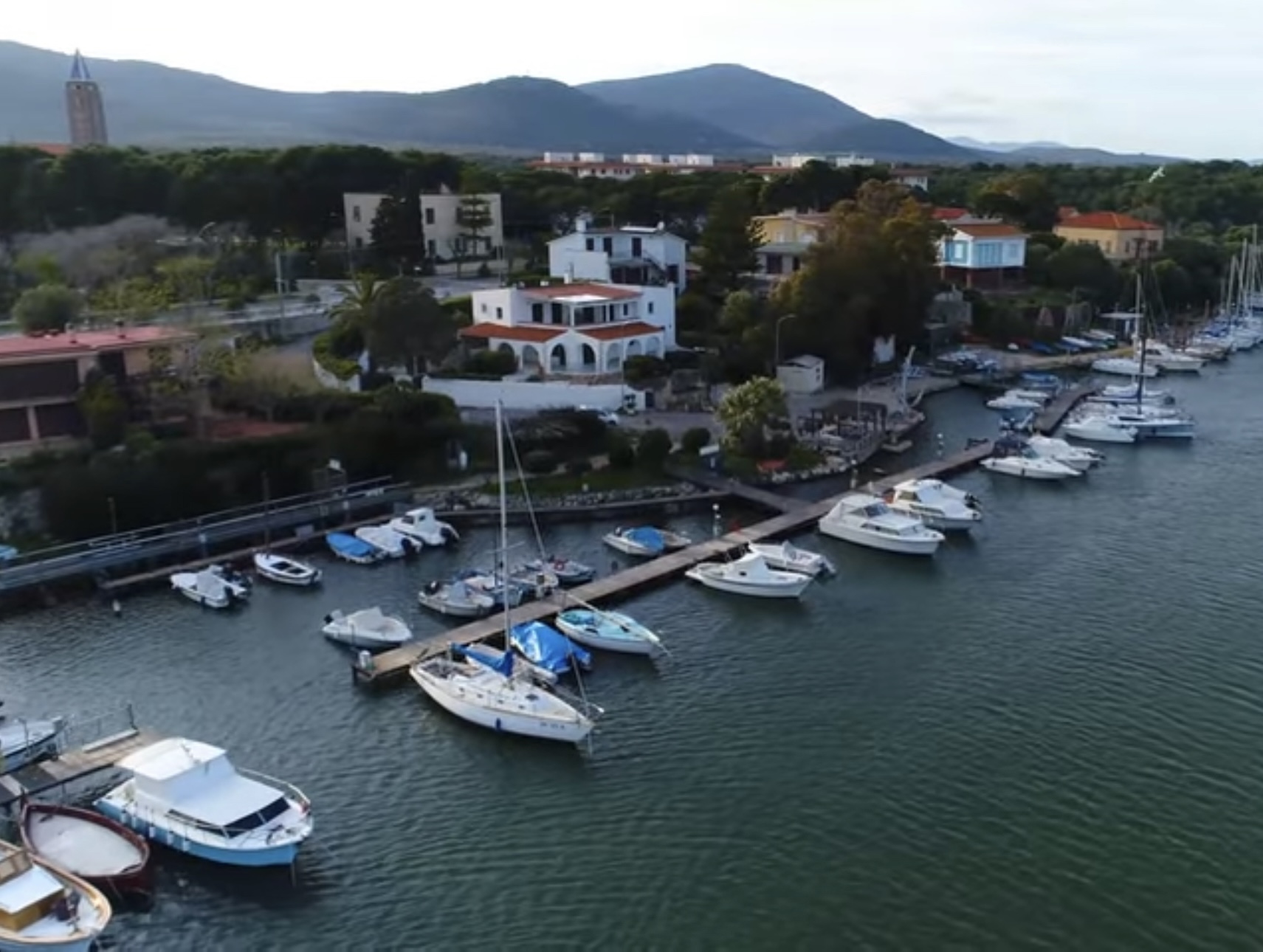 Fertilia harbor with small boats and the town behind it near Alghero