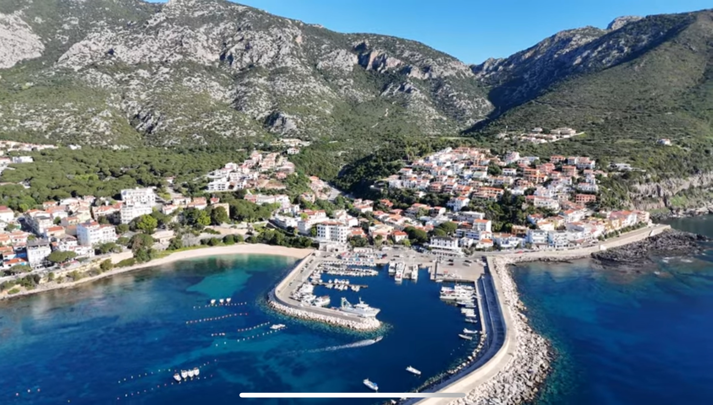 Aerial view of Cala Gonone harbor, town beach and the Supramonte mountains in eastern Sardinia